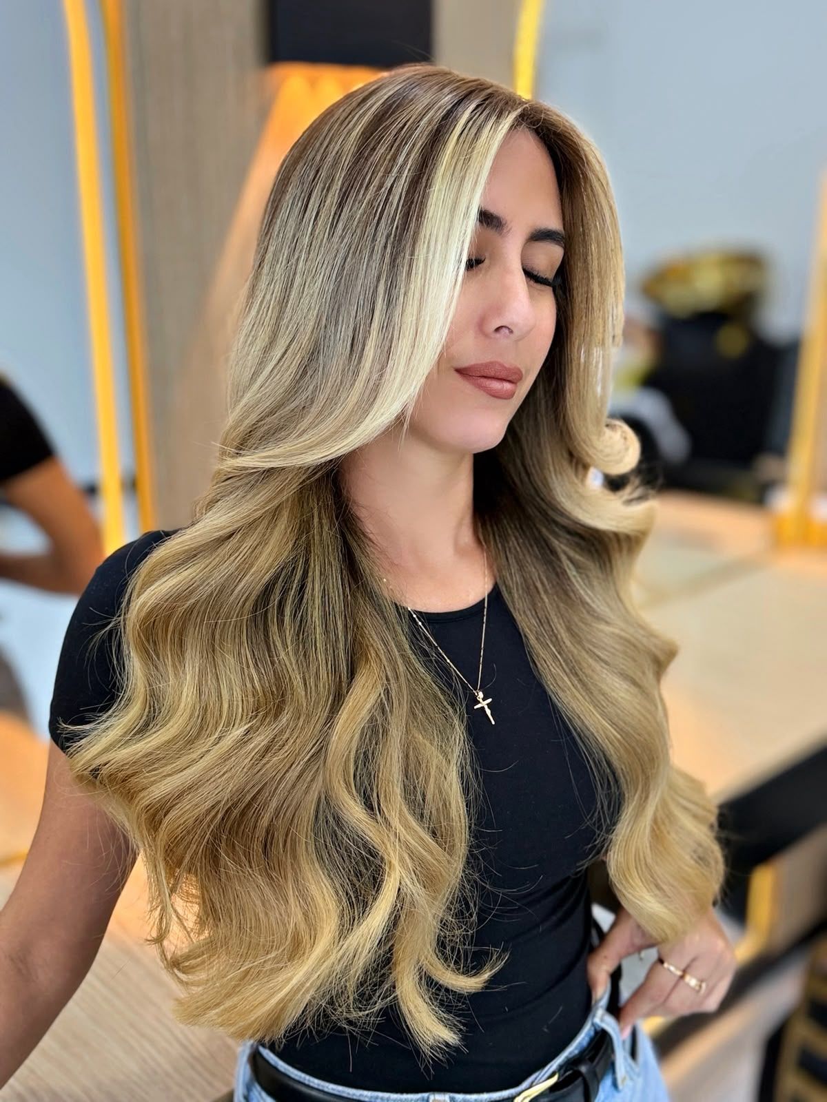 Clienta con balayage rubio y ondas largas en el salón